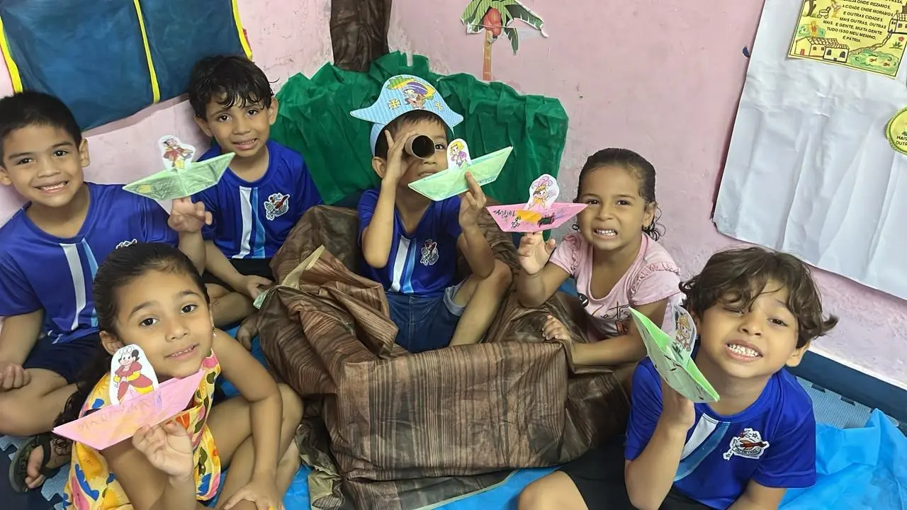 Crianças com barquinhos de papel e chapéus de pirata numa dramatização em sala