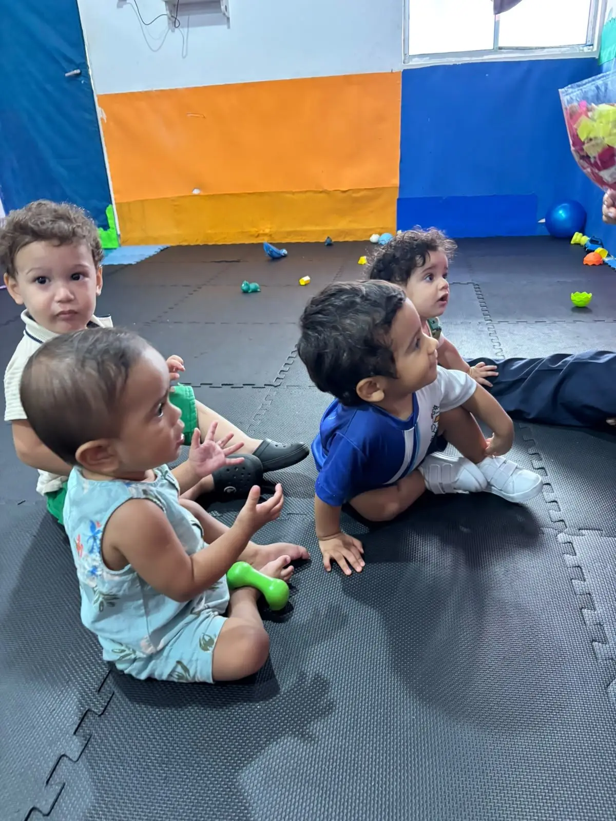 Bebês do berçário sentados no tapete, brincando