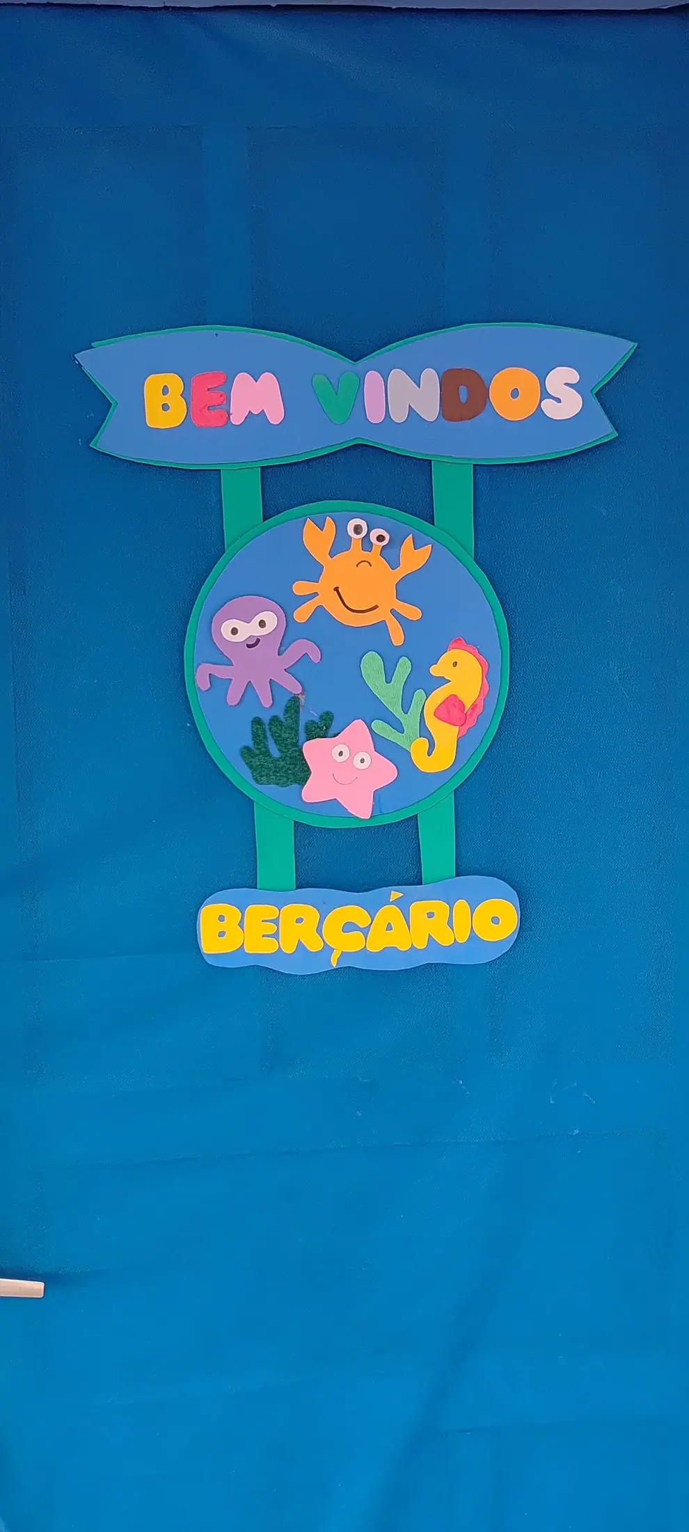 Porta azul do Berçário, com a placa de boas-vindas