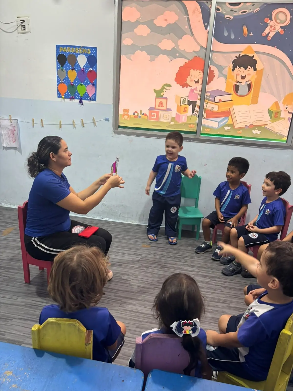 Professora contando uma história com fantoche para a turma sentada em roda