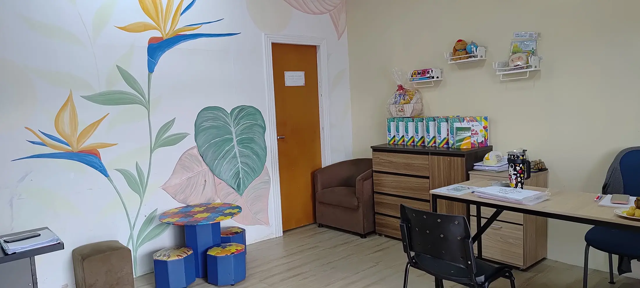 Sala da direção, clara, com plantas pintadas na parede